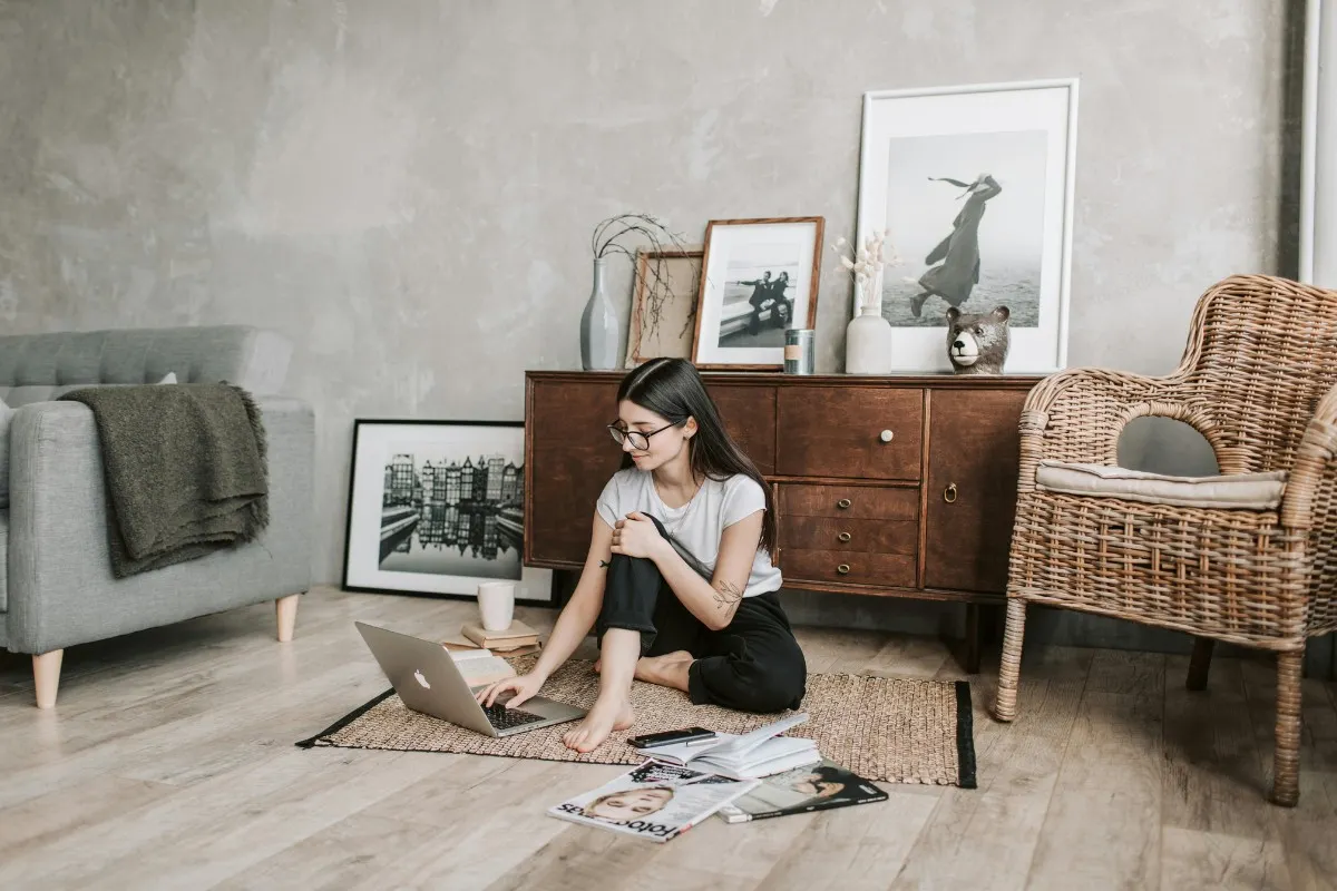Thảm trải sàn sợi thiên nhiêu cho phòng khách của cô gái đen kính ngồi làm việc bằng laptop dưới sàn nhà