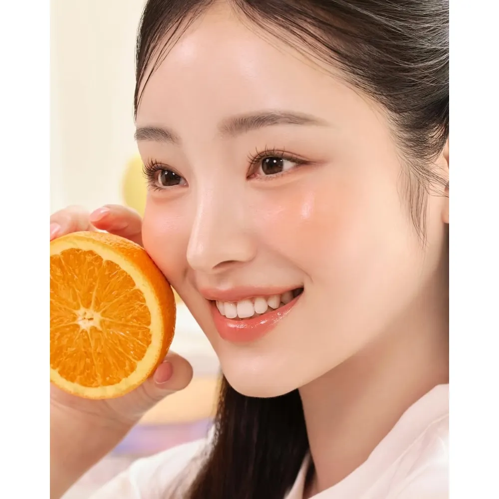 Cô gái mỉm cười bên quả cam chứa nhiều vitamin C.