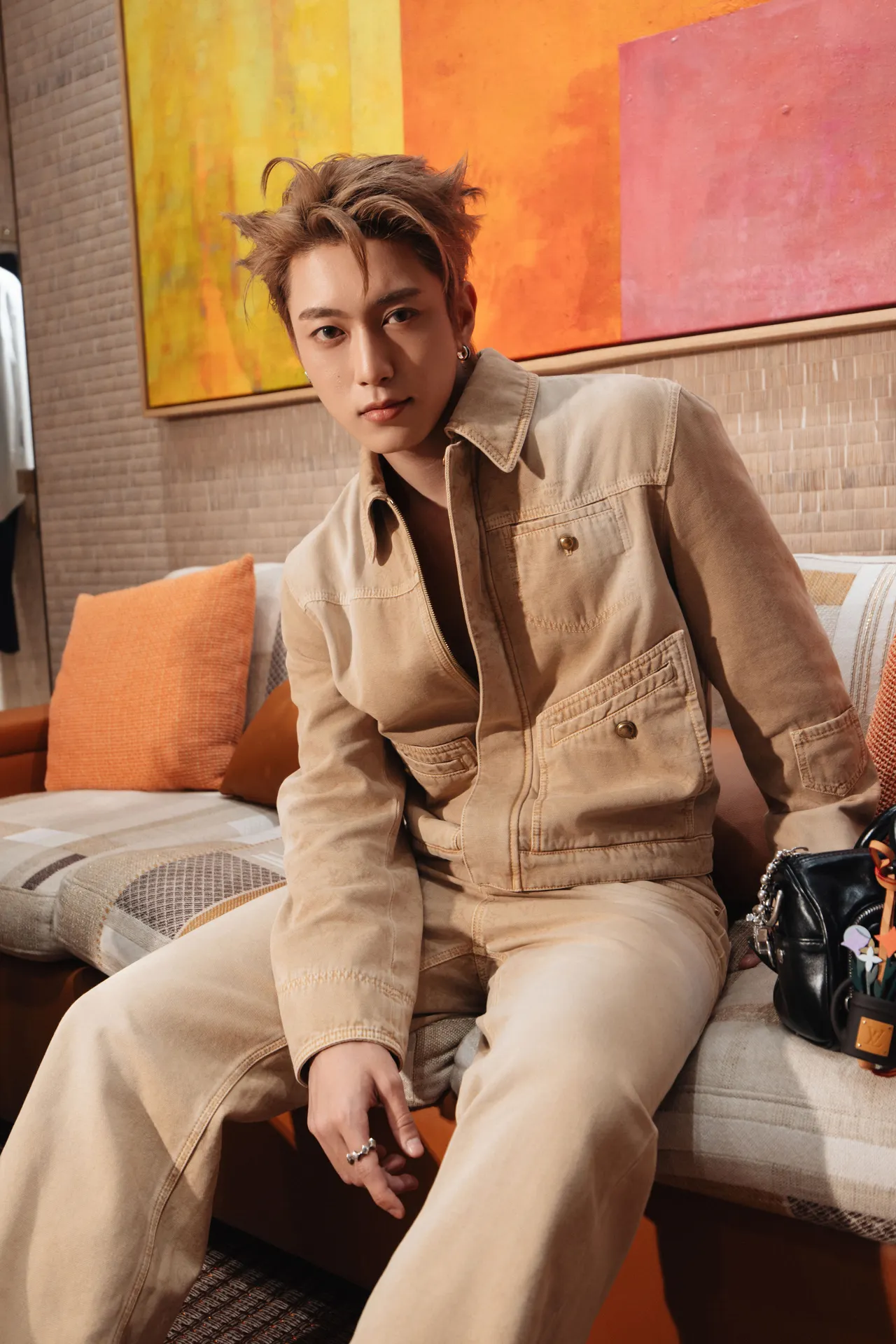 Thái Lê Minh Hiếu chọn trang phục denim màu be đồng bộ gồm áo khoác và quần ống đứng kết hợp cùng túi xách đen và giày sneakers họa tiết vàng.