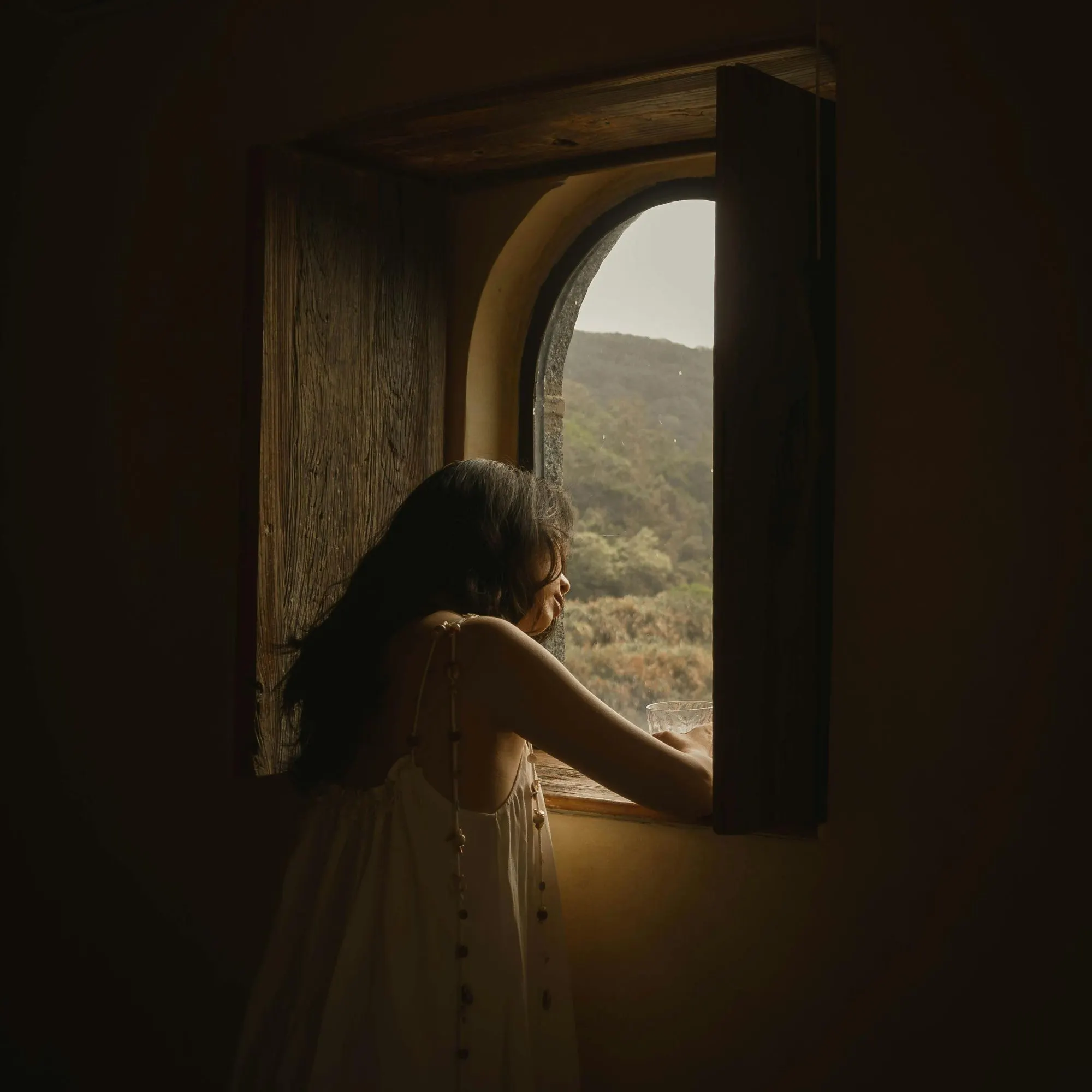 Cô gái mặc đầm trắng tựa vào cửa sổ