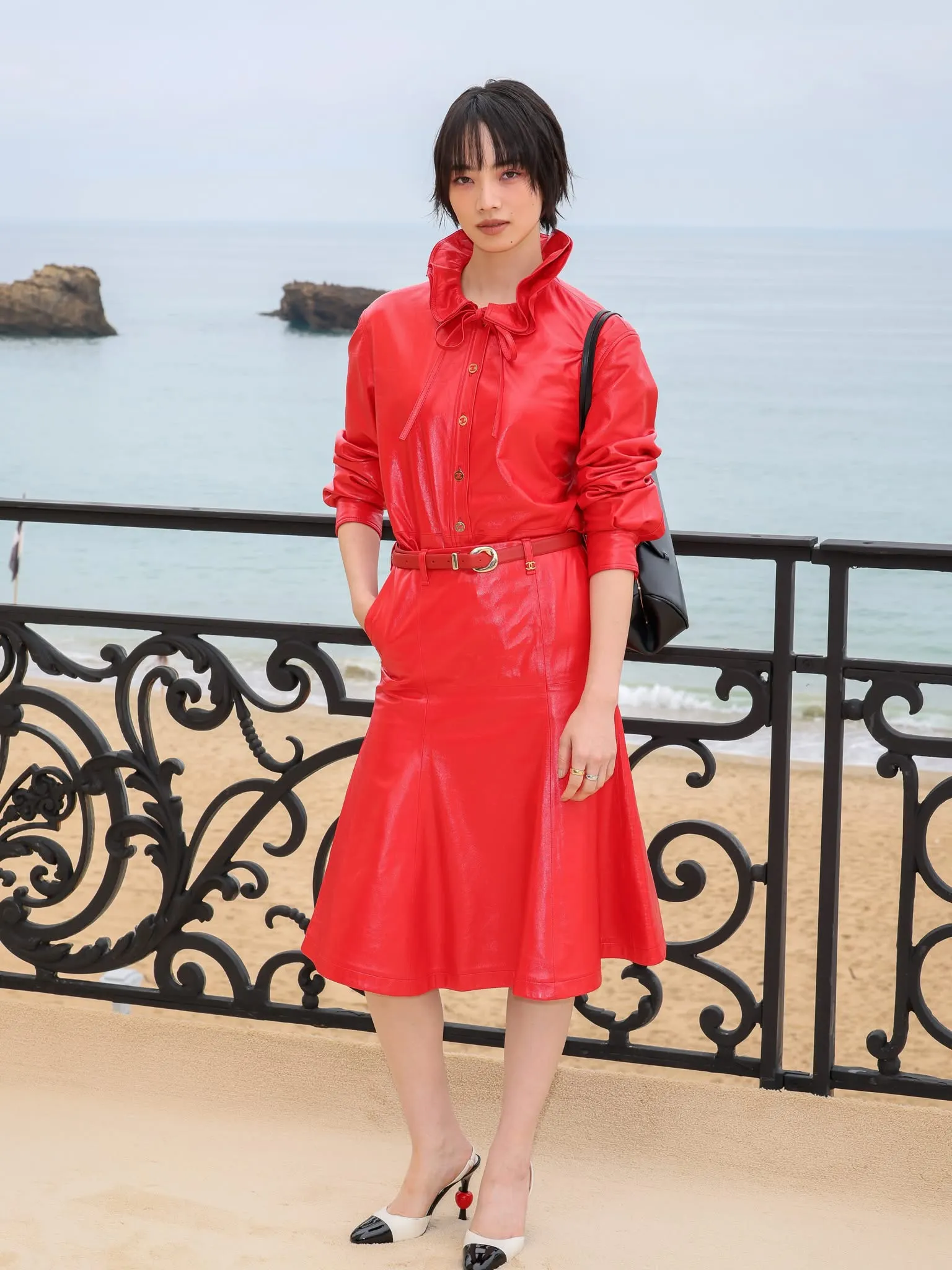 Nana Komatsu chọn một thiết kế nguyên cây đỏ bằng chất liệu da bóng cao cấp. Phần áo có chi tiết cổ xếp bèo điệu đà kết hợp cùng hàng khuy vàng sang trọng.