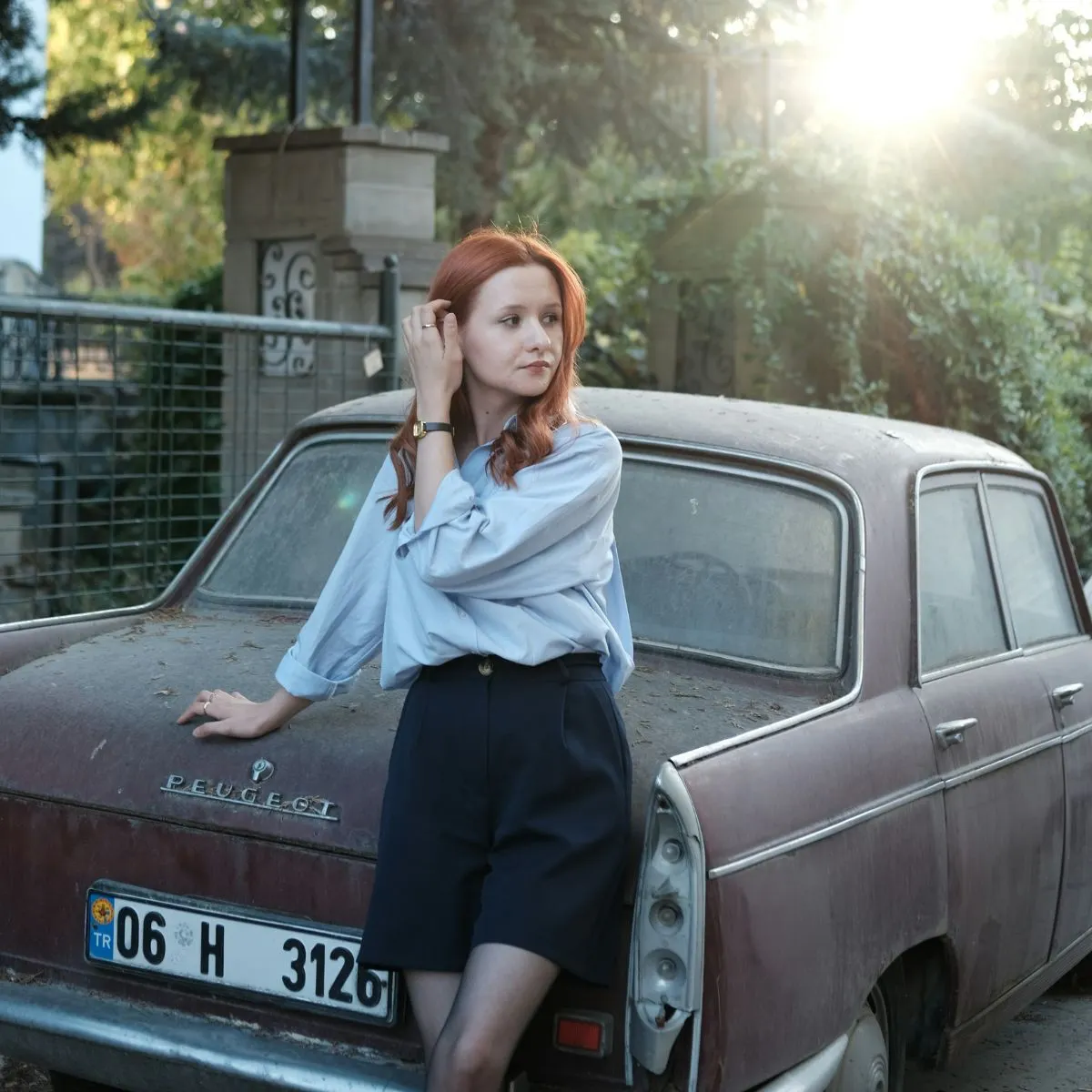 Cô gái áo sơ mi xanh dương tóc đỏ đứng kế xe hơi thực hiện trắc nghiệm DISC 