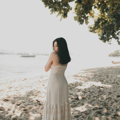 cô gái mặc váy trắng đứng bên bờ biển