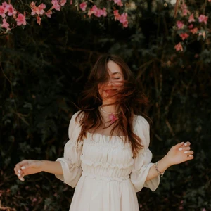 cô gái cung hoàng đạo tháng 12/2025 xõa tóc mỉm cười đứng dưới tán cây hoa