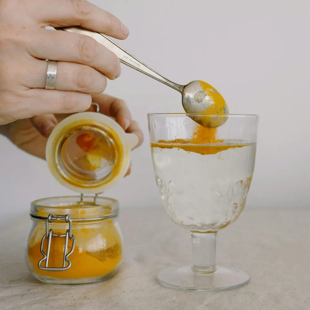 cô gái đang pha bột nghệ vào ly nước