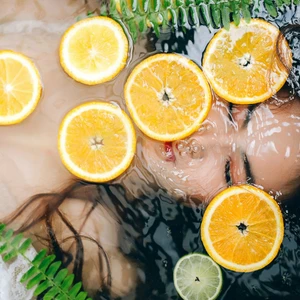 người phụ nữ ngâm mình trong bồn nước có cam