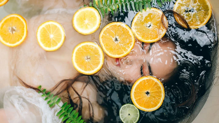 người phụ nữ ngâm mình trong bồn nước có cam