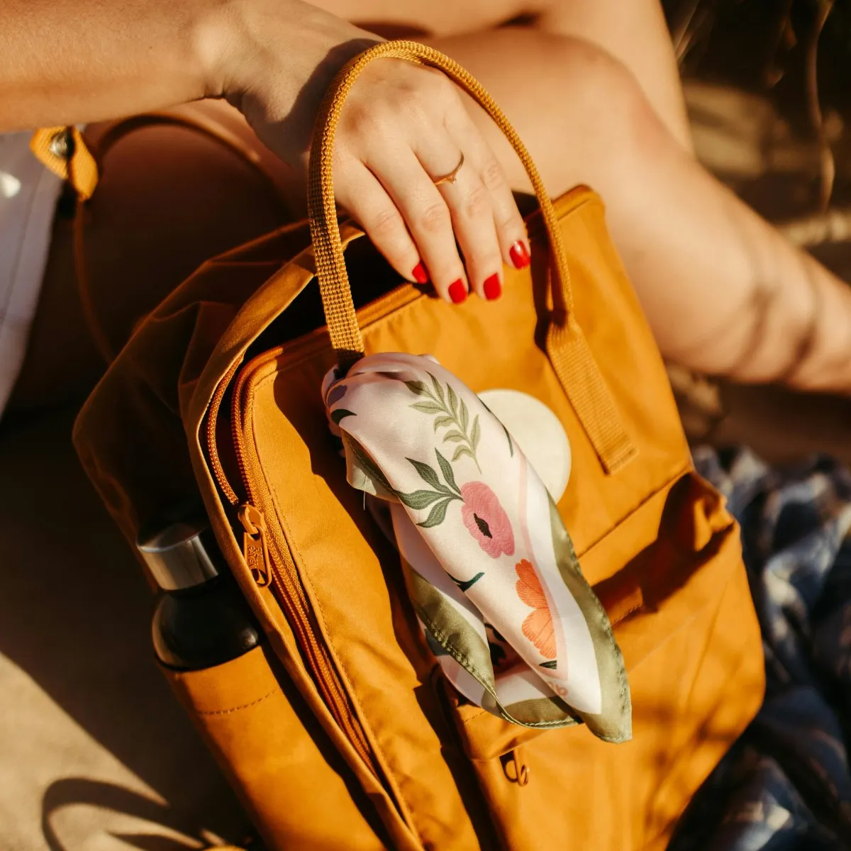 Tay cô gái giữ túi xách màu nàu cột khăn hoa