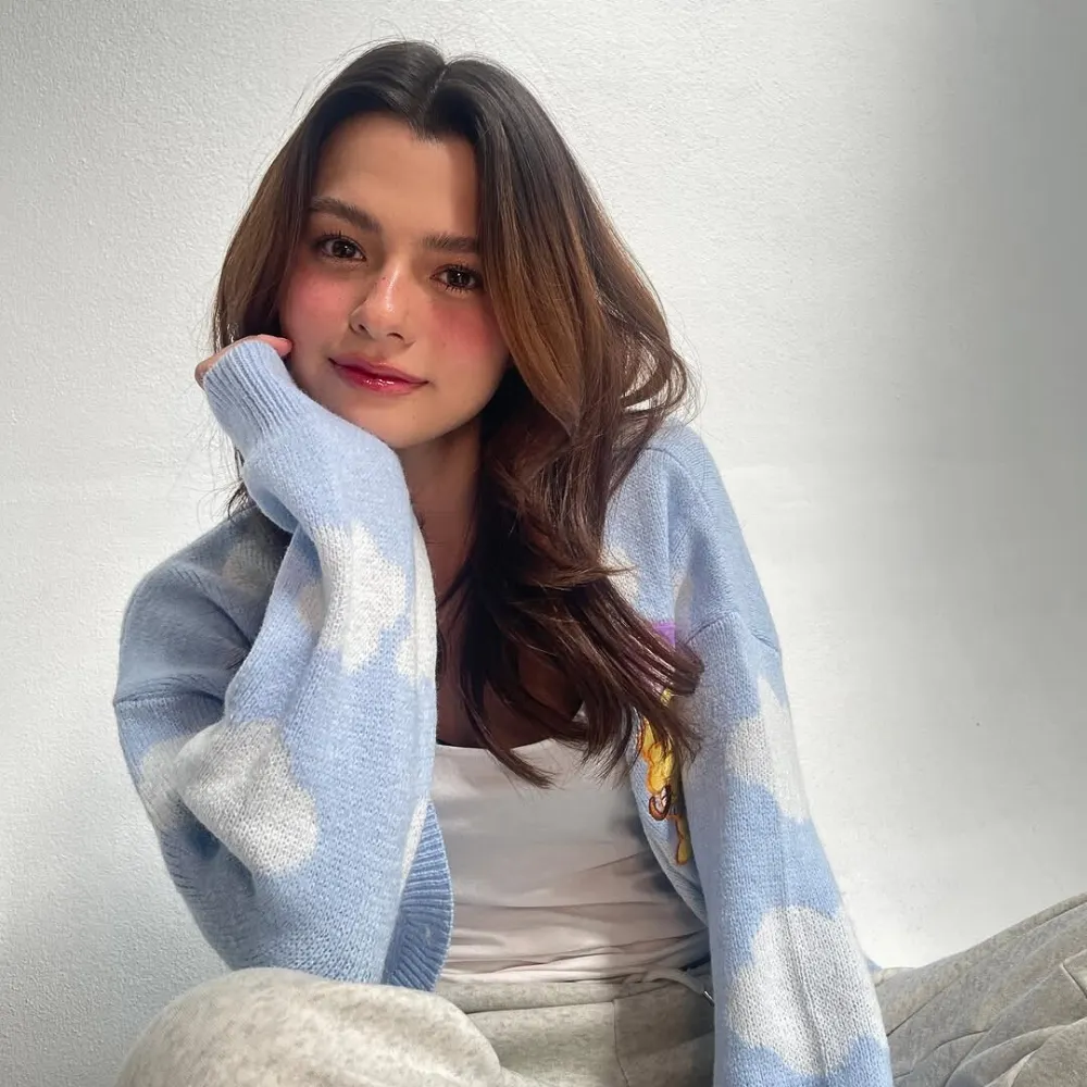 Rebecca mang áo cardigan chống tay lên cằm