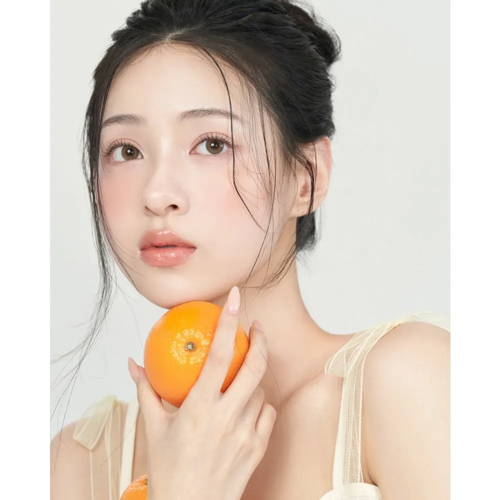 Cô gái cầm quả cam để tạo dáng trước ống kính.