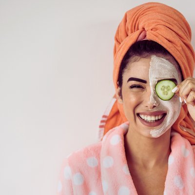 cô gái đội khăn tắm và đắp dưa leo một bên mặt để giảm quầng thâm mắt