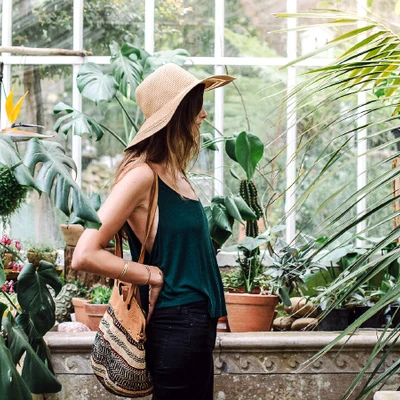 cô gái mặc áo dây màu xanh đứng giữa nhà kính