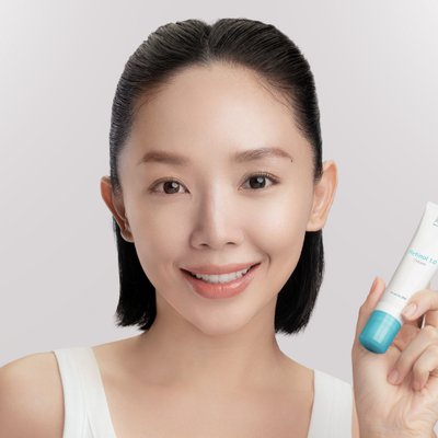 Obagi - ca sĩ Tóc Tiên mặc áo tank top màu trắng, buộc tóc nửa đầu, tay cầm tuýp kem dưỡng retinol của Obagi và nhìn chính diện vào camera để chụp ảnh chân dung
