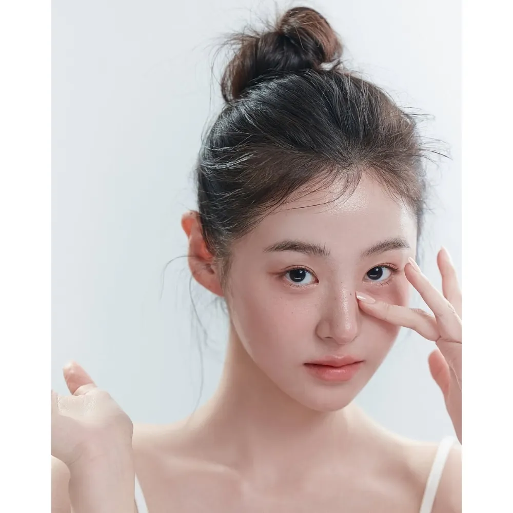Cô gái búi tóc đặt tay lên phần mũi có mụn đầu đen.